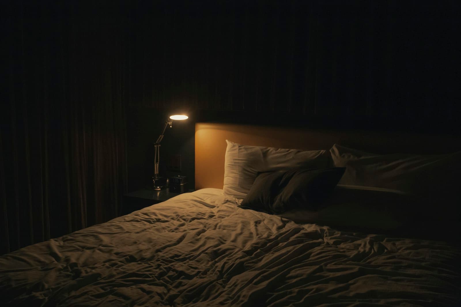 A softly lit bedside lamp glowing beside a bed at night