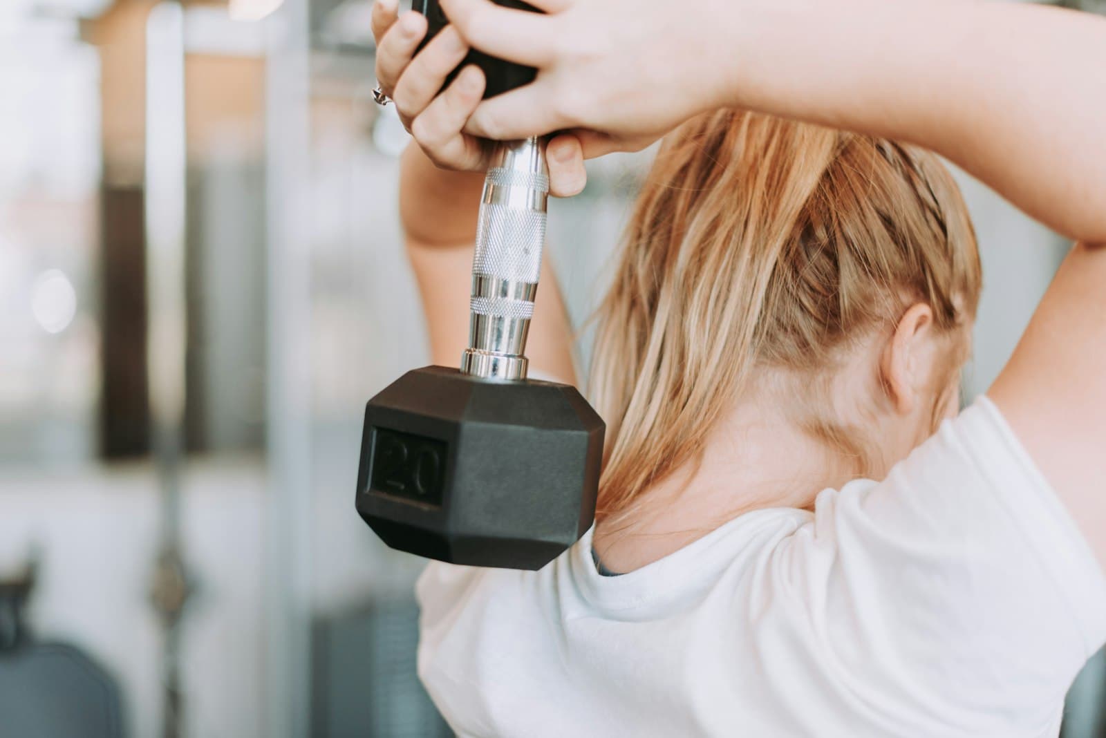 A woman lifting a dumbbell, seen from behind